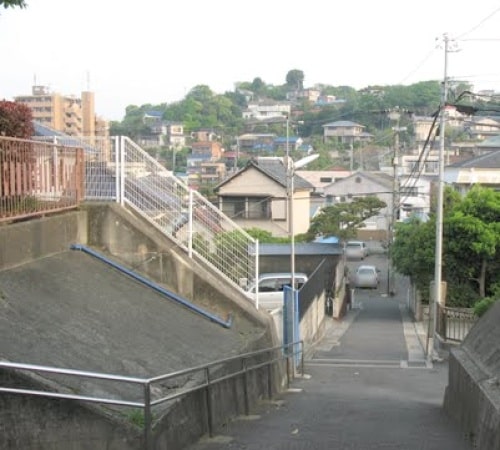 保育園の門から坂を見下ろした所。傾斜のやや強い坂の上に保育園は位置しています