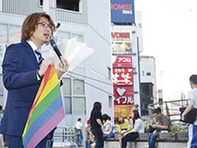 性的マイノリティを象徴するレインボーフラッグを持ち通行人に呼びかける藤野英明市議（＝17日、横須賀中央Ｙデッキ）